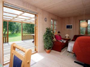 un hombre sentado en una silla en un porche cubierto en 8 person holiday home in R dby, en Kramnitse
