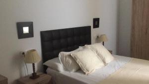a bedroom with a bed with a black headboard and two lamps at ENTRETORRES Apartamento Turístico in Olivenza