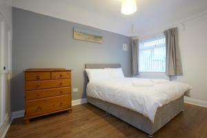 a bedroom with a bed and a dresser and a window at Spacious Stylish Residence in Leeds