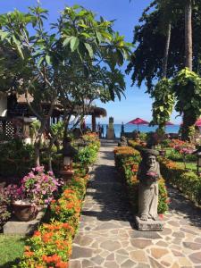 a walkway through a garden with flowers and a statue at Puri Mas Boutique Resort & Spa in Senggigi