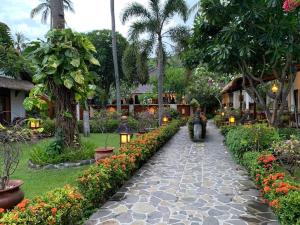 a path in a garden with flowers and a person on a motorcycle at Puri Mas Boutique Resort & Spa in Senggigi