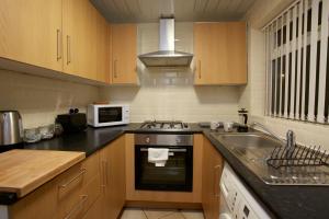 a kitchen with a sink and a stove and a microwave at Spacious Stylish Residence in Leeds