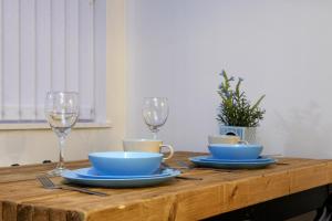 a wooden table with two wine glasses and blue bowls at Spacious Stylish Residence in Leeds