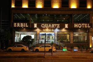 dos coches estacionados frente a un hotel por la noche en Erbil Quartz Hotel en Erbil