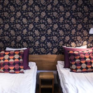 a hotel room with two beds with pillows and a wallpaper at Stora Hotellet Osby in Osby