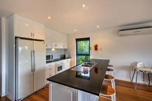 a kitchen with white appliances and a black counter top at Blue Gum Retreat in Coles Bay