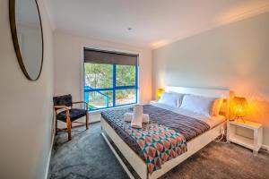 a bedroom with a bed with a chair and a window at Blue Gum Retreat in Coles Bay