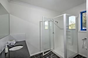 Un baño blanco con ducha y lavabo. en Blue Gum Retreat, en Coles Bay 11 fotos más