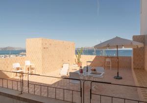 a patio with an umbrella and chairs and a table at Moll Petit Apartments - Turismo de Interior in Can Picafort