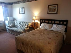 a bedroom with a bed and a couch at Traveller's Inn in Dawson Creek