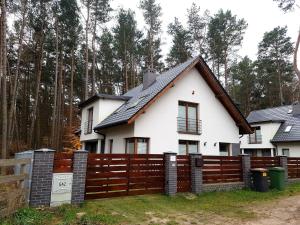 ein weißes Haus mit einem Holzzaun in der Unterkunft Dom na Skraju in Łukęcin