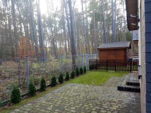 einen Hinterhof mit einem Zaun und einer Hütte mit Bäumen in der Unterkunft Dom na Skraju in Łukęcin