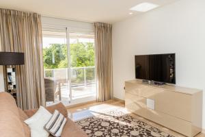 ein Wohnzimmer mit einem Sofa und einem Flachbild-TV in der Unterkunft Golden Gardens Apartment Javea Arenal by Rock Rentals in Jávea