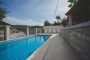 a swimming pool in front of a house at Apartmani Bauk in Pučišća