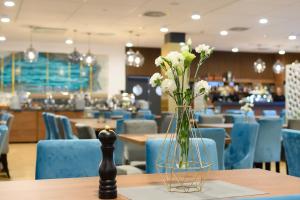 un jarrón de flores sobre una mesa en un restaurante en Aparthotel Termy Uniejów, en Uniejów