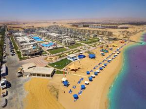 eine Luftansicht auf einen Strand mit Sonnenschirmen und dem Meer in der Unterkunft SeaVille Beach Hotel by Elite Hotels & Resorts in Ain Suchna
