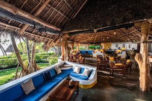 a restaurant with blue couches and tables and chairs at Pongwe Beach Hotel in Pongwe