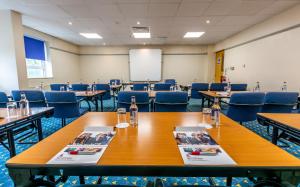 a conference room with tables and chairs and a screen at Britannia Hotel Wigan in Standish