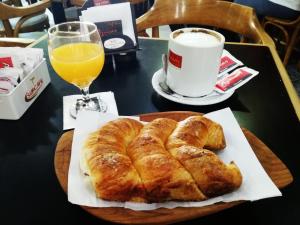 un tavolo con un piatto di pane e una tazza di succo d'arancia di Hotel Crystal a Neuquén