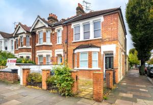a red brick house with white windows on a street at Stunning 2-bed flat w/ garden patio in West London in London