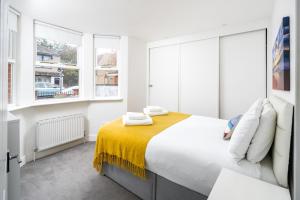 倫敦的住宿－Stunning 2-bed flat w/ garden patio in West London，白色卧室设有大床和窗户