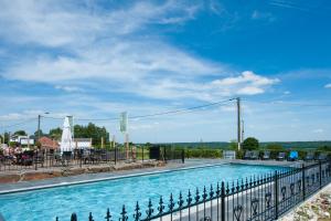 een groot zwembad met een hek eromheen bij Chalet Camping Natuurlijk Limburg in Remersdaal