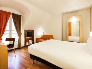 una camera d'albergo con un grande letto e una sedia di ibis Versailles Château a Versailles