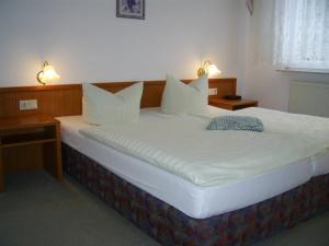 ein großes Bett mit weißer Bettwäsche und Kissen in einem Zimmer in der Unterkunft Hotel Kirchner in Tharandt
