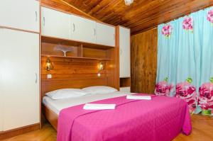 a bedroom with a pink bed with a pink blanket at Guest house Mediteran Relax in Makarska