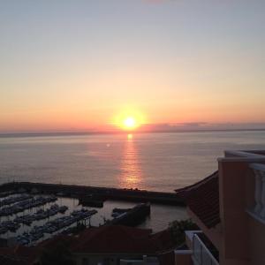 - un coucher de soleil sur l'océan et un port de plaisance dans l'établissement APARTAMENTO VISTAS AL MAR, à Santiago del Teide