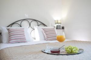 a tray with a glass of orange juice and grapes on a bed at George Poros house in Poros