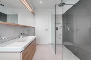uma casa de banho branca com um lavatório e um chuveiro em Apartmány HRÁDEČEK em Mladé Buky