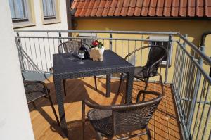 uma mesa com 2 cadeiras e uma garrafa de vinho na varanda em Das Altstadthaus em Volkach