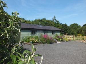 a green house with flowers in front of it at The Potting Shed And The Garden Shed Self Catering in Carmarthen