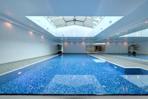 a swimming pool with blue water in a building at 3 City Apartments - Waterlane Valhalla in Gdańsk