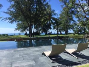 a swimming pool with two lounge chairs next to it at Baan mai khao apartment in Mai Khao Beach