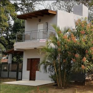 a white house with a balcony and a tree at Las Piedras del Paso in Paso de la Patria