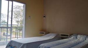 a bedroom with two beds and a large window at Las Piedras del Paso in Paso de la Patria