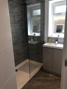 a bathroom with a shower and two sinks and a mirror at Jonan House in Deal +11 photos