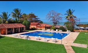 Una gran piscina con sillas y una casa. en Hotel Cumuruxatiba, en Cumuruxatiba
