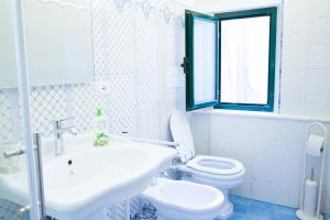 a white bathroom with a toilet and a sink at Casa Cardi in Sperlonga