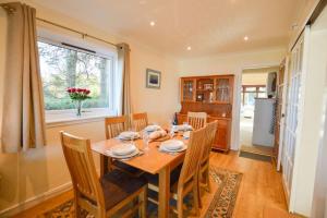 a dining room with a table and chairs and a window at An Cala in Connel