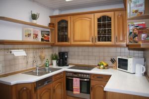 a kitchen with wooden cabinets and a sink and a microwave at Ferienwohnung Am Park Weimar in Weimar