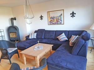 ein Wohnzimmer mit einem blauen Sofa und einem Tisch in der Unterkunft Reethaus Zickersche Berge - Apt. 01 in Gager