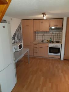 uma cozinha com armários de madeira e um frigorífico branco em Apartment Öffingen 77 em Fellbach