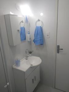 een witte badkamer met een wastafel en een spiegel bij Quarto com café nas Pitangueiras in Guarujá