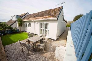 a small white house with a table and chairs at Mawgan Porth Apartments in Mawgan Porth