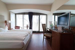 a hotel room with a bed and a desk with a television at Hotel Am Blauen Wunder in Dresden