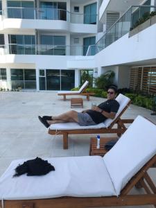 un hombre sentado en un sillón frente a un edificio en Santa Marta Rodadero Sur Playa salguero A 200 Mts Del Mar, en Santa Marta