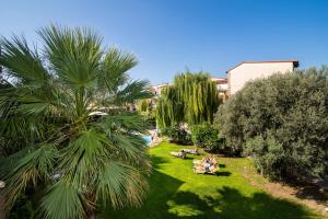 a palm tree in a yard with people sitting on a lawn at Villas Duc - Rhodes in Ialyssos